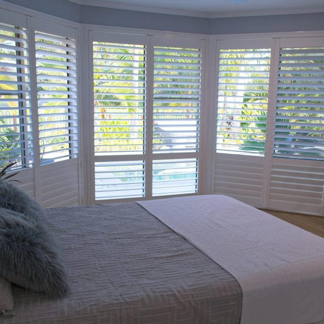 plantation shutters next to a bed