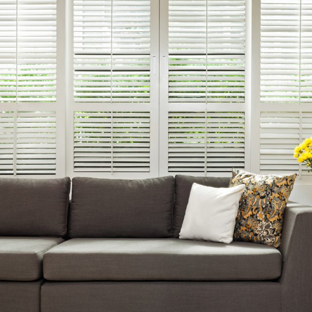 venetian blinds behind a brown sofa